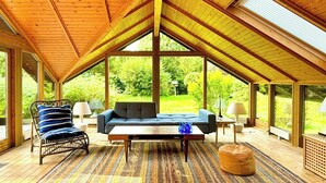 A spacious room with a high ceiling, a sofa, a chair, a coffee table, and a patterned rug. - Traditional Kalmar house close to the beach (sjaellands odde)