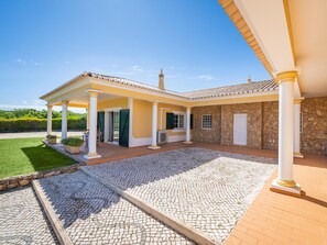 A covered outdoor area with a stone wall, a tiled roof, and a paved patio. - Charming Villa with Pool & Garden in Vale da Lama (Odiáxere, Lagos)