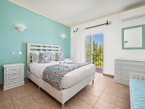 A bedroom with a bed, bedside tables, a dresser, a balcony with a view, and a window with curtains. - Charming Villa with Pool & Garden in Vale da Lama (Odiáxere, Lagos)