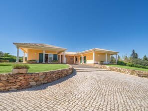 A two-story house with a stone wall and a cobblestone driveway. - Charming Villa with Pool & Garden in Vale da Lama (Odiáxere, Lagos)