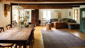 A dining area with a wooden table, chairs, a chandelier, and a large rug. - The Hallandsåsen lighthouse, a natural retreat (Munka-ljungby)