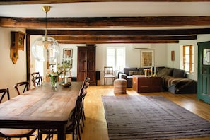 A dining area with a wooden table, chairs, a chandelier, and a large rug. - The Hallandsåsen lighthouse, a natural retreat (Munka-ljungby)
