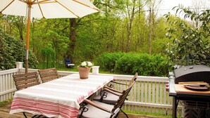 An outdoor deck with a table and chairs, a grill, and a potted plant. - The Hallandsåsen lighthouse, a natural retreat (Munka-ljungby)