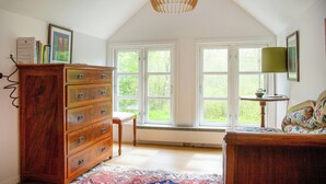A room with a wooden dresser, a chair, a bed, and large windows allowing natural light. - The Hallandsåsen lighthouse, a natural retreat (Munka-ljungby)