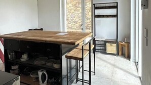 A modern kitchen with a wooden ceiling, a built-in stove, and a large window.