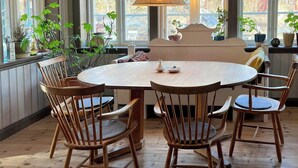 Un coin repas avec une table ronde, des chaises en bois, un banc et des plantes en pot.