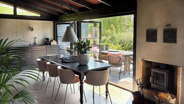 Een moderne keuken met een eethoek, houten vloeren en een open haard.