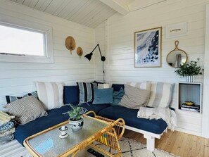 Ein gemütliches Zimmer mit einem blauen Sofa, einem kleinen Tisch mit Kerze und einem Topfpflanzen.