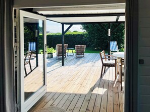 Eine offene Terrasse mit Holzboden, einem Tisch, Stühlen und einer überdachten Sitzecke.
