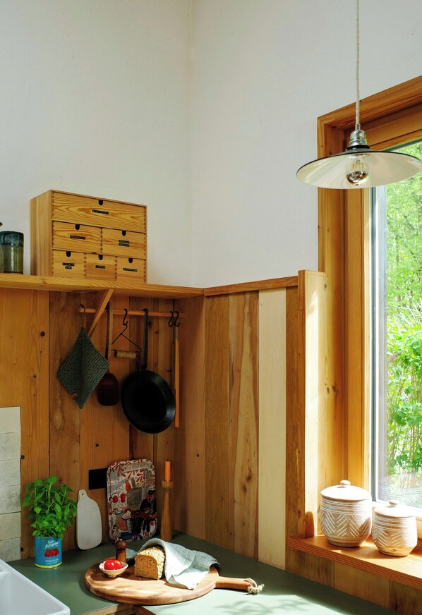 A kitchen with wooden walls, a window, and a hanging pot rack.