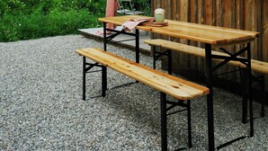 A wooden cabin with a gravel patio, a table, and benches. - Creatively converted wooden shed in the forest (Palling)