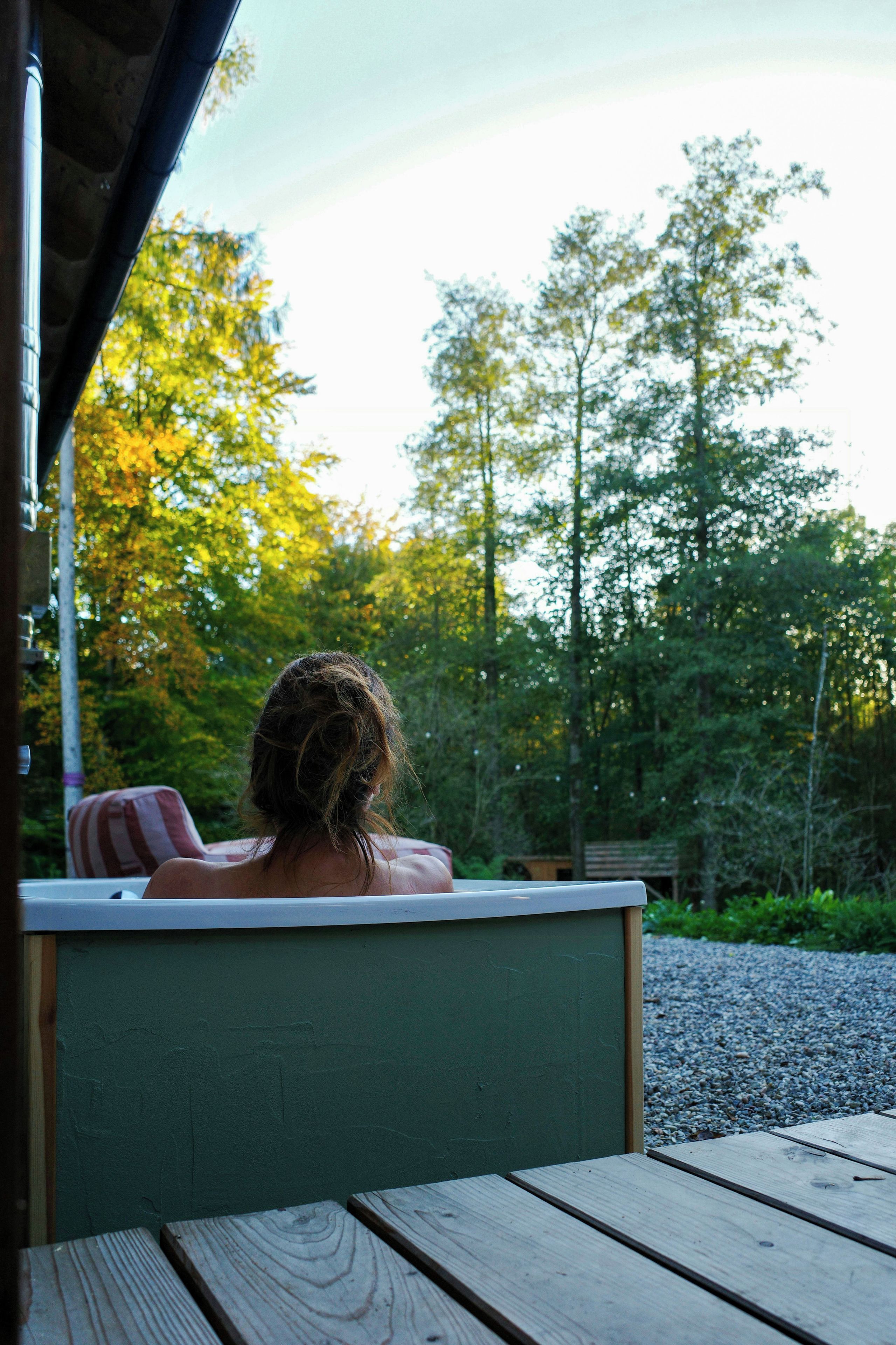 A person seated at a table with a view of a forested area.