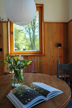 A wooden table with a book and a vase of flowers.
