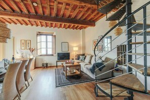 Ein geräumiges Wohnzimmer mit Holzboden, einer Couch, einem Couchtisch und einer Treppe.