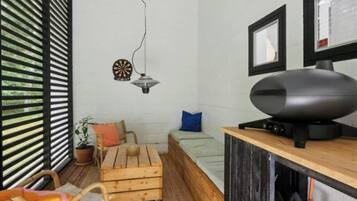Habitació petita amb un llit, una taula, una cadira, una planta en test i un televisor sobre un suport.