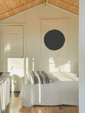 Quarto com cama, porta, decoração circular na parede e teto de madeira.