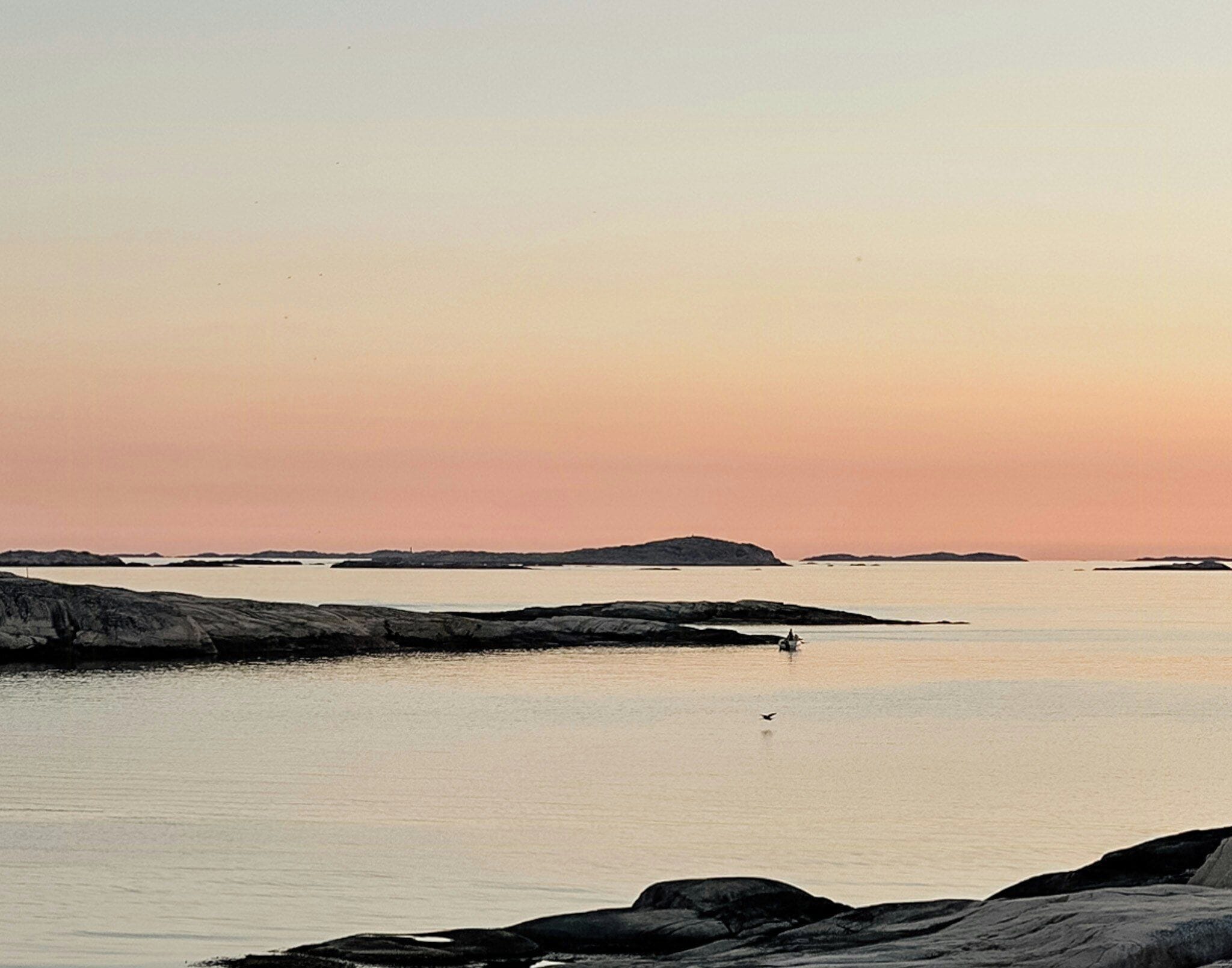 A coastal landscape with calm water, rocky shores, and distant islands.