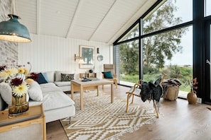 A modern living room with a large window, a sofa, a coffee table, and a hanging chair.