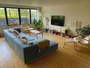 A living room with a sectional sofa, a flat-screen TV, and a large window.