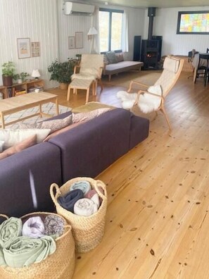 Ein gemütliches Wohnzimmer mit einer Couch, Sesseln, einem Holztisch, einem Kamin und einem Fernseher.
