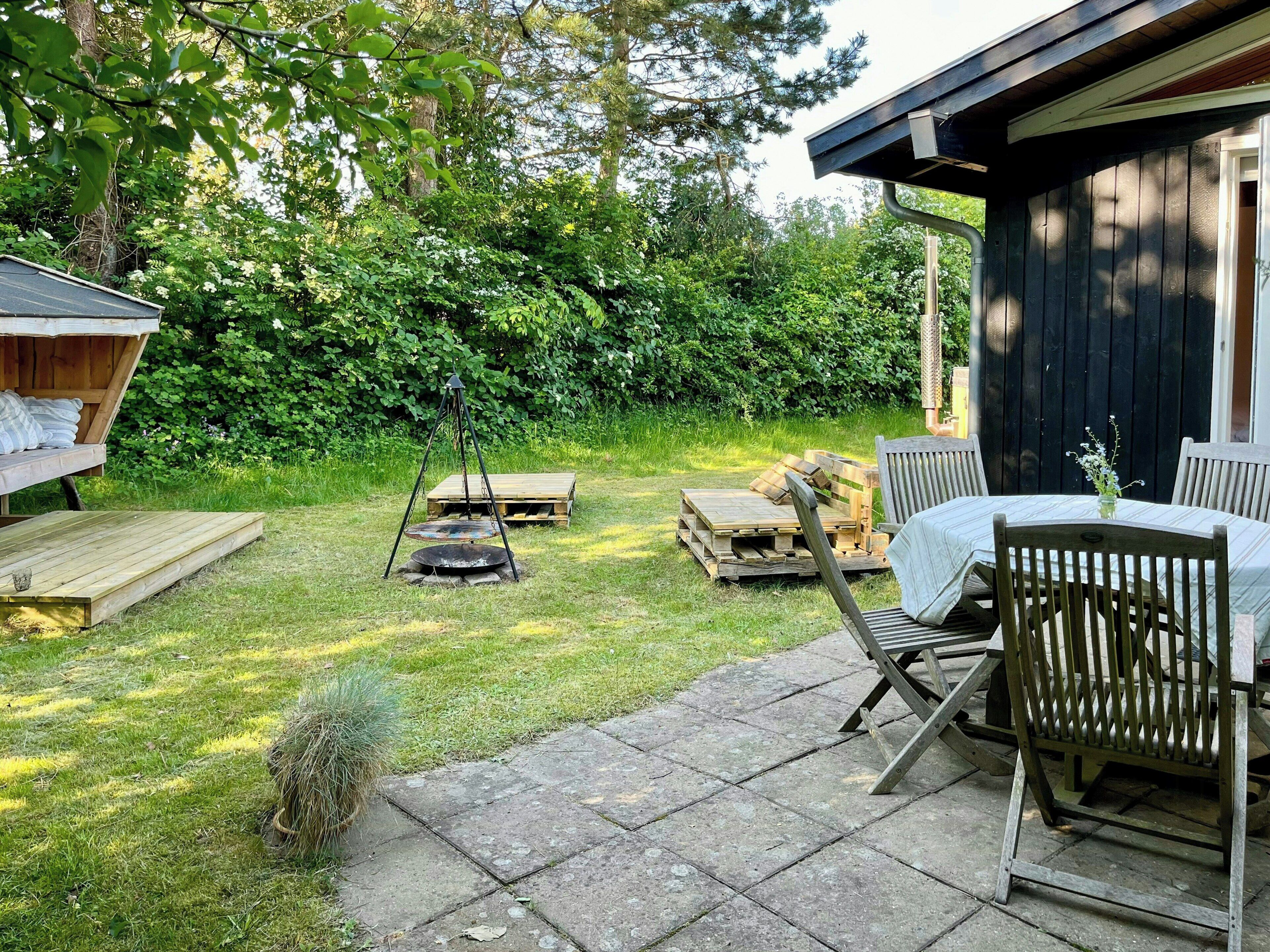 A wooden deck with a table and chairs, a swing, and a fire pit in a backyard.
