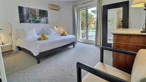 Ein Hotelzimmer mit Bett, Schreibtisch, Stuhl, Spiegel und Blick ins Freie.