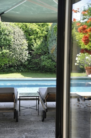 A view of a swimming pool with lounge chairs and a covered patio area. - Villa with heated pool near the Alpilles (Saint Rémy de Provence)