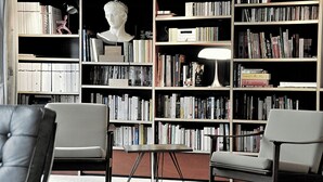 Eine Bibliothek mit Bücherregalen, einer Büstenstatue und zwei Sesseln.