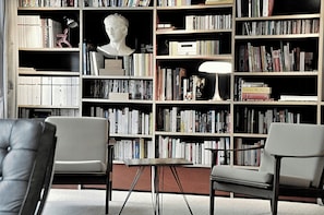 A library with bookshelves, a bust sculpture, and two chairs. - Villa with heated pool near the Alpilles (Saint Rémy de Provence)