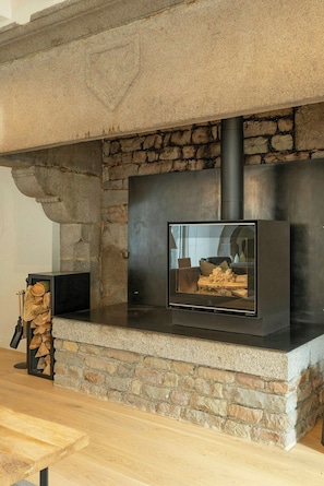 Une cheminée en pierre avec un écran de télévision moderne, un banc en pierre et un espace de rangement pour le bois.