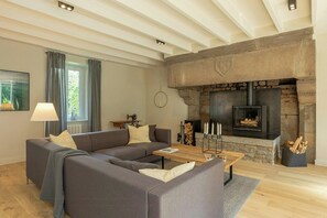 Un salon avec une cheminée en pierre, un canapé, une table basse et une lampe.