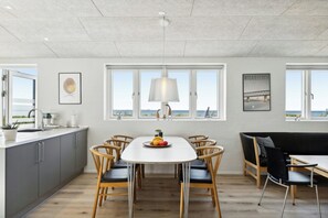Eine moderne Küche mit Essbereich, großen Fenstern und Blick auf das Meer.