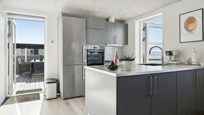 Een moderne keuken met een groot keukenblok, ingebouwde apparatuur en uitzicht naar buiten.
