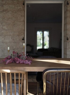 Ein Holztisch mit Blumen, Kerzen, einem Stuhl und einer Steinsäule.