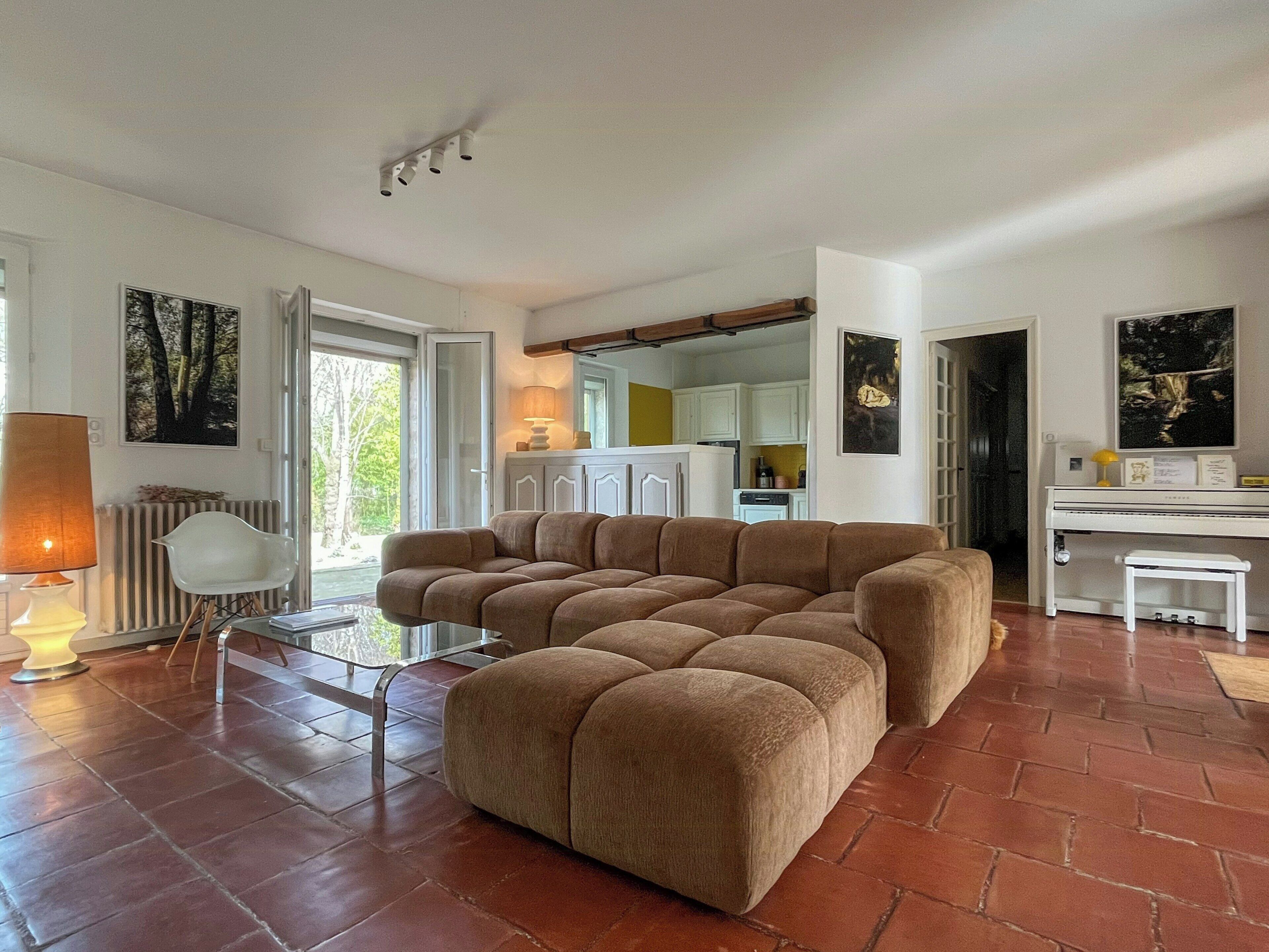Ein Wohnzimmer mit Ecksofa, einem Esstisch und einer Küche im Hintergrund.