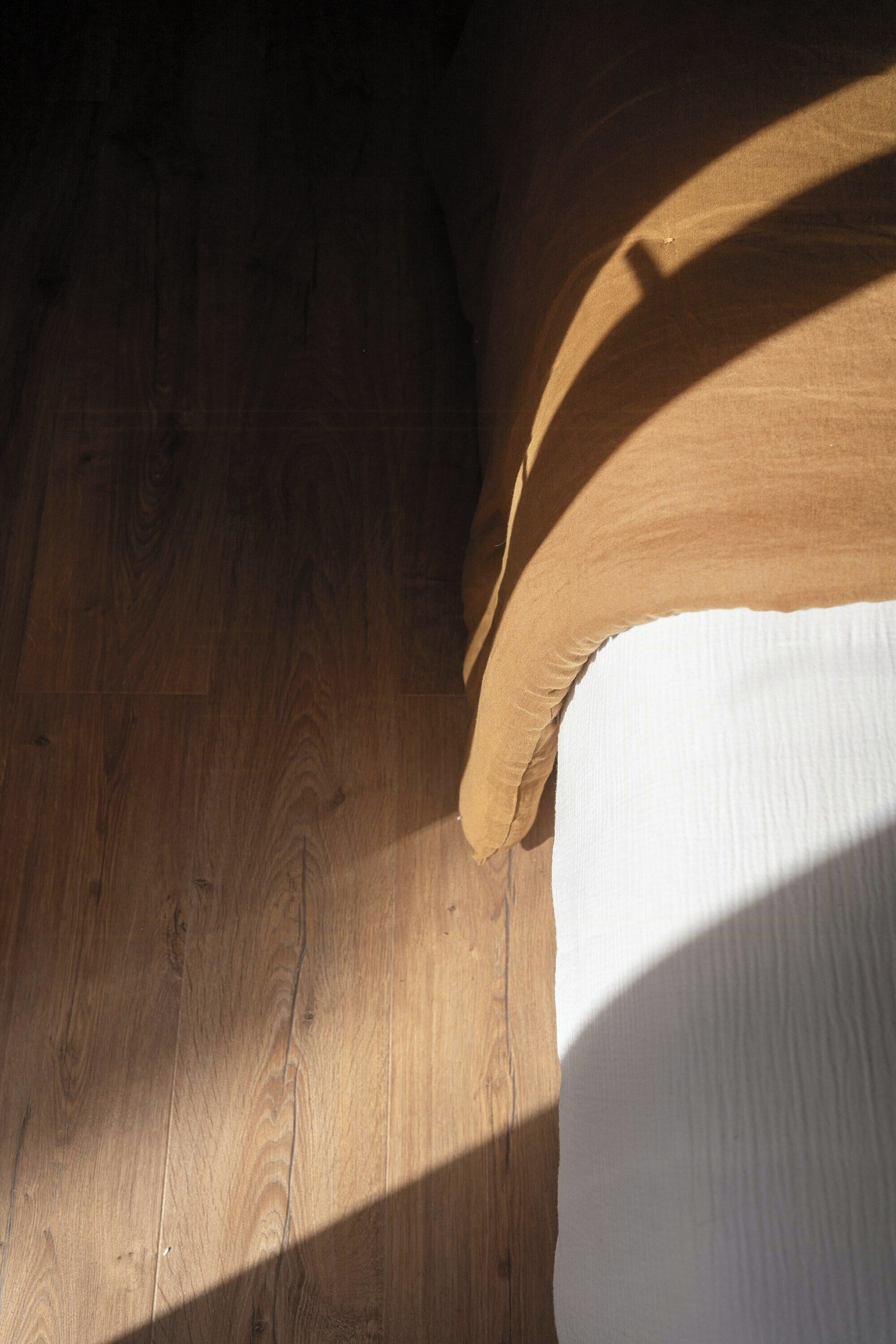 Ein Holzboden mit einem Schatten, der von einem Kopfkissen geworfen wird.