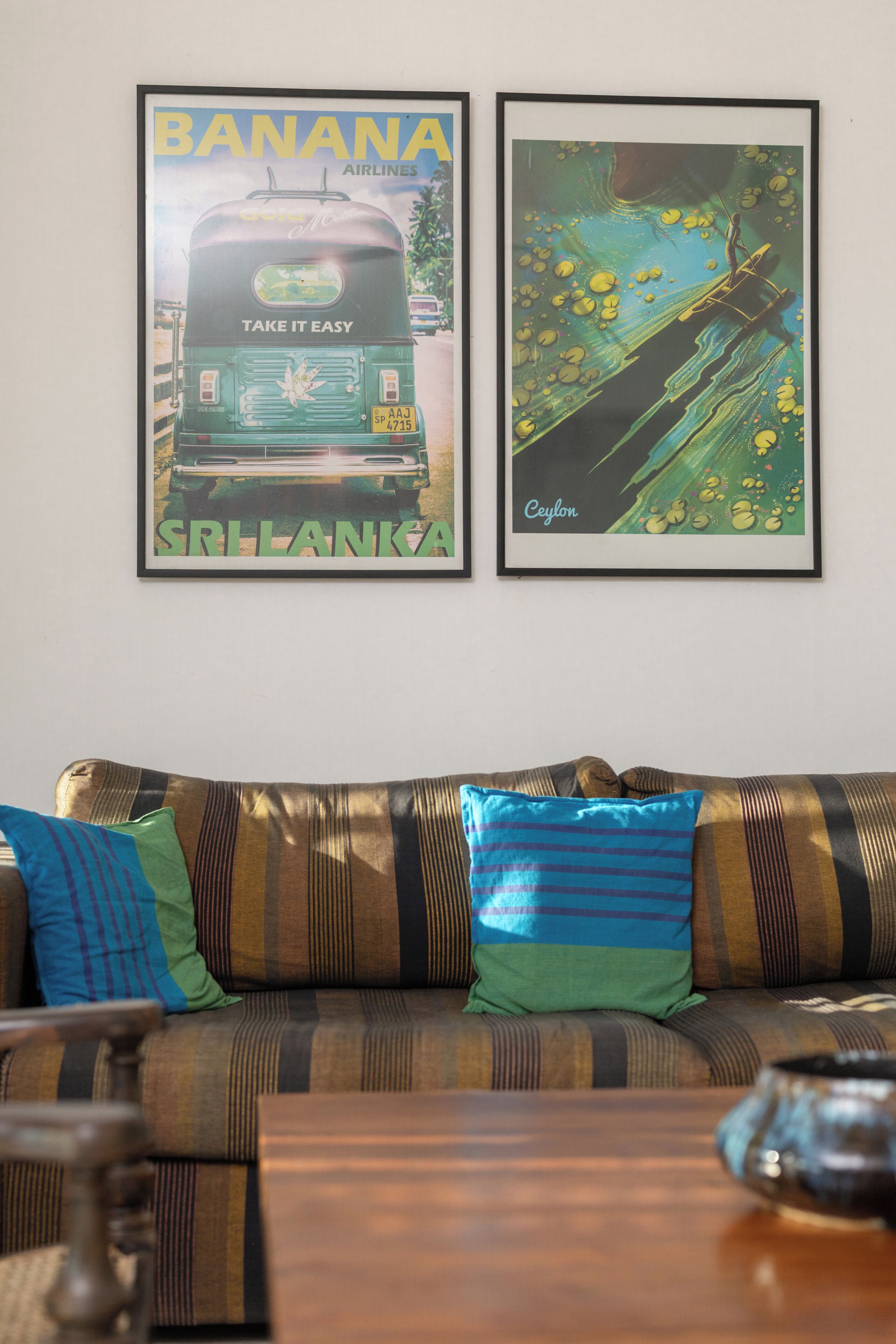 A living room with a sofa, pillows, and two framed pictures on the wall.
