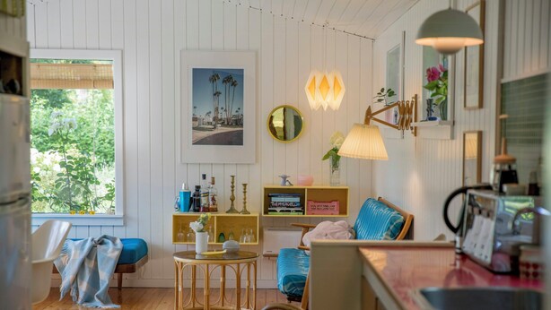 Een gezellige woonkamer met een houten vloer, een blauwe bank, een kleine ronde tafel en een boekenkast.