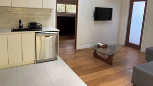 Una cocina moderna con lavavajillas, una mesa pequeña y un televisor instalado en la pared.