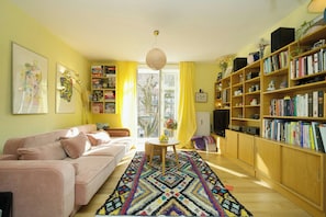 Un salon comprenant un canapé, une table basse, une bibliothèque et une fenêtre avec des rideaux.