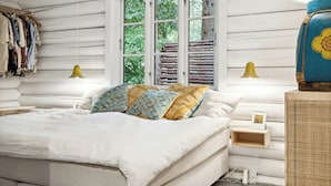 A bedroom with a bed, bedside lamps, a dresser, and a window with a view of greenery. - Scenic and idyllic log summer house by Arresø (Frederiksværk)