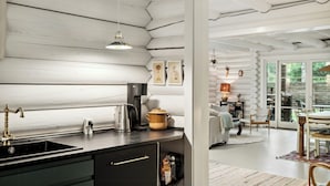 A kitchen with a sink, stove, and countertop. There is a dining area with a table and chairs. - Scenic and idyllic log summer house by Arresø (Frederiksværk)