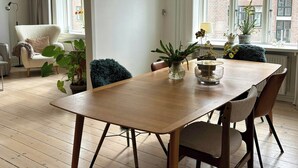 Un espace repas comprenant une table en bois, des chaises, un luminaire suspendu et des plantes en pot.