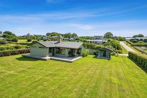 Une maison moderne dotée d’une grande pelouse, d’une terrasse et d’un petit jardin.