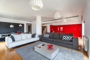 Ein modernes Wohnzimmer mit einem grauen Sofa, einem weißen Couchtisch und einer roten Akzentwand.
