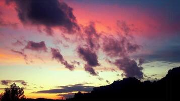 Un coucher de soleil avec des nuages au-dessus d’un paysage montagneux.