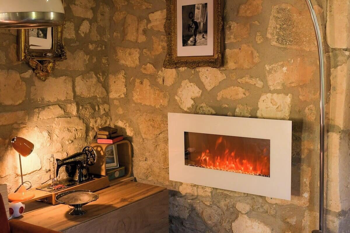 A stone wall with a fireplace, a sewing machine, and a lamp.