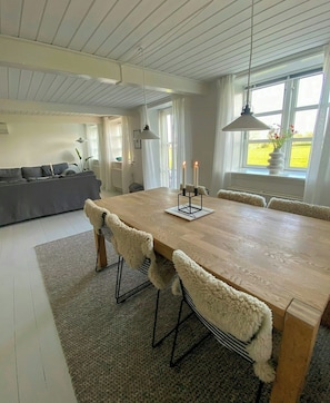 Et moderne spiseområde med et træbord, bløde stole og stearinlys.