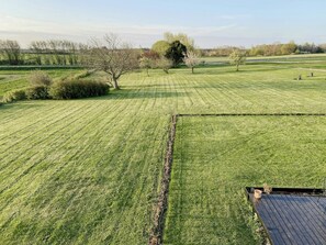 A well-maintained grassy field with a wooden deck and a tree in the foreground. - Farmhouse charm and cottage life on Bornholm (Gudhjem)