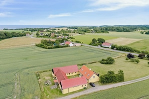 Oversigtsbillede fra luften af et landligt område med marker, en bondegård og en vej.